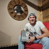 Kevin Lötscher pose avec un exemplaire du livre dans lequel il raconte son histoire et comment il s'est relevé de son accident.